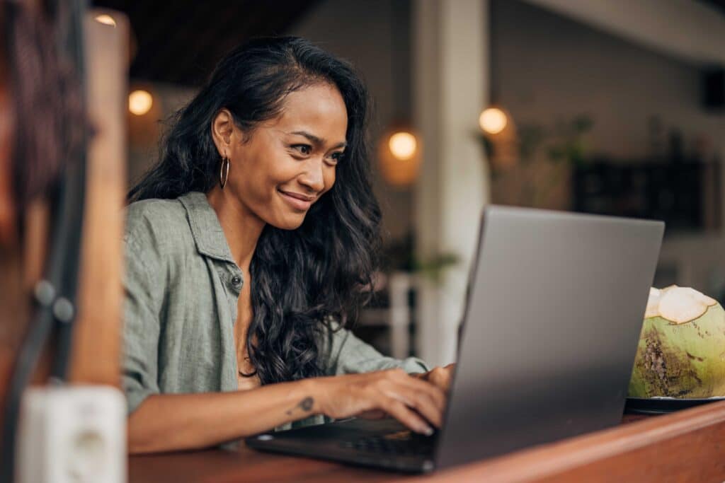 Sitzende Dame lächelt, während sie auf ihrem Laptop tippt