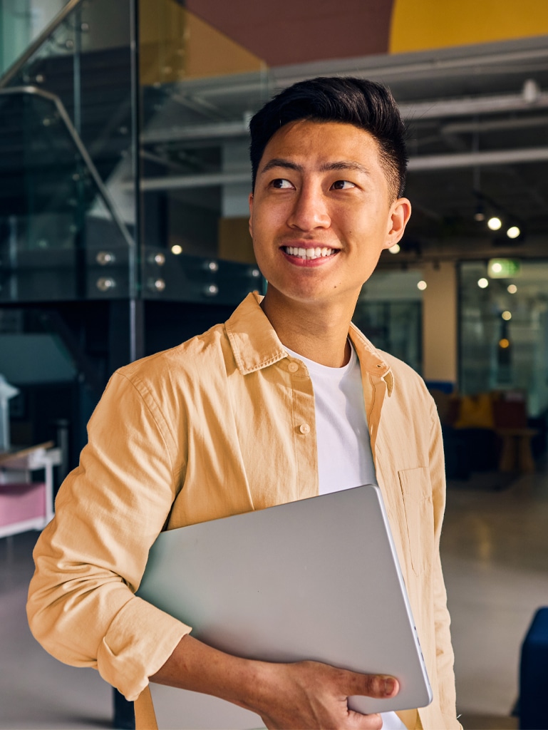 Young asian freelancer smiling and holding laptop in modern office
